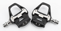 Detailed top-down close-up view of the Promend PD-R97P W road bike pedals on a white background, highlighting the carbon fiber texture finish and silver stainless steel wear plates.