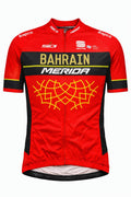Front view of Bahrain Merida short sleeve cycling jersey in crimson red and black featuring a gold geometric pattern on the chest