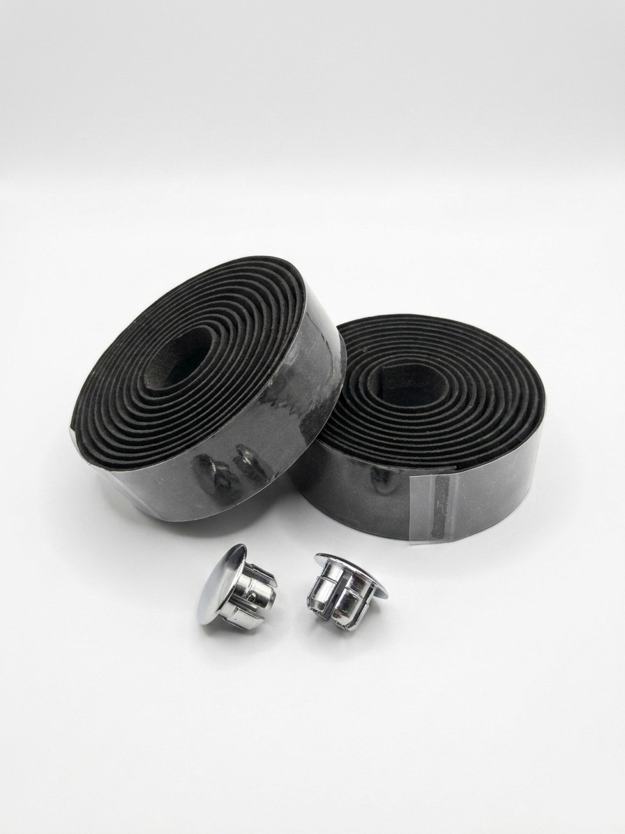 Two rolls of premium black bicycle handlebar tape secured in clear packaging alongside two metallic chrome handlebar end plugs on a white background