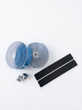 Premium sky blue bicycle handlebar tape rolls with a clean, smooth matte texture as shown in image, displayed alongside two metallic chrome bar end plugs and two black adhesive finishing strips on a bright white background.