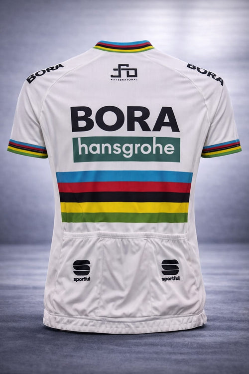 Back view of the white Bora-Hansgrohe cycling jersey showing three elastic rear storage pockets, Sportful logos, and a prominent black Bora Hansgrohe graphic below a rainbow band.