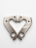 Dual silver metallic DH004 rear derailleur hangers arranged symmetrically in a heart shape on a clean white background.