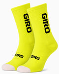 A pair of Giro crew-height performance cycling socks in vibrant high-visibility safety yellow with bold black typography branding and a contrast white toe box, displayed against a plain background.