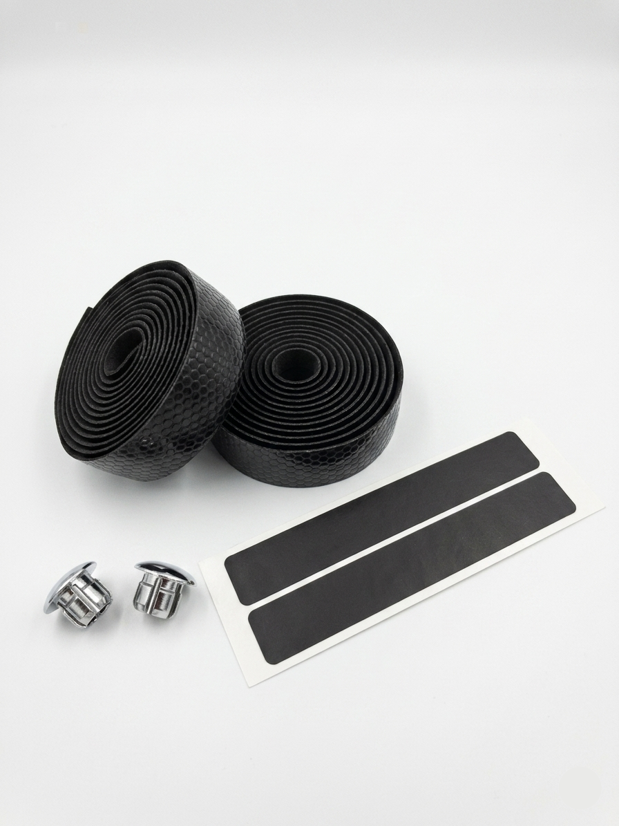 Premium classic black bicycle handlebar tape rolls with a textured hexagon honeycomb surface pattern, paired with two shiny chrome bar end plugs and black adhesive finishing strips on a clean white background.