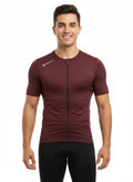Front studio view of a male model wearing a tight-fitting, deep maroon Reeck short sleeve cycling jersey with a small white brand logo on the right collarbone.