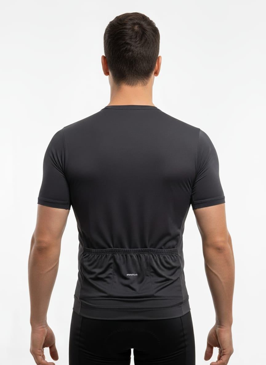 Rear view of a male model wearing the dark blue Reeck race fit cycling jersey, showcasing the triple back pockets and a horizontal silver reflective safety strip near the hem.