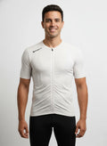 Front studio view of a male model wearing a tight compression-fit, classic white Reeck short sleeve cycling jersey with a full-length white zipper and a black brand logo on the right shoulder.