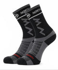 A pair of NORTHWAVE performance crew cycling socks in a black and grey colorway with a subtle red accent name on the toe, showcasing geometric NW branding on the upper cuff and a textured mesh design over the foot, displayed upright against a clean white background