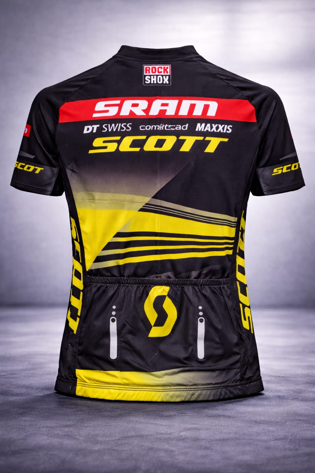 Back view of the Scott-SRAM cycling jersey showcasing three rear storage pockets with a large yellow Scott logo, a red SRAM shoulder panel, and a RockShox logo on the collar.