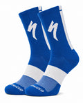 A pair of SPECIALIZED crew cycling socks in a vibrant royal blue colorway featuring a white midfoot compression band, a vertical white stripe down the back, and the iconic white lightning bolt logo on the upper cuff, displayed upright against a clean white background.