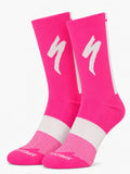 A pair of SPECIALIZED crew cycling socks in a vibrant neon pink colorway featuring a white midfoot compression band, a vertical white stripe down the back, and the iconic white lightning bolt logo on the upper cuff, displayed upright against a clean white background